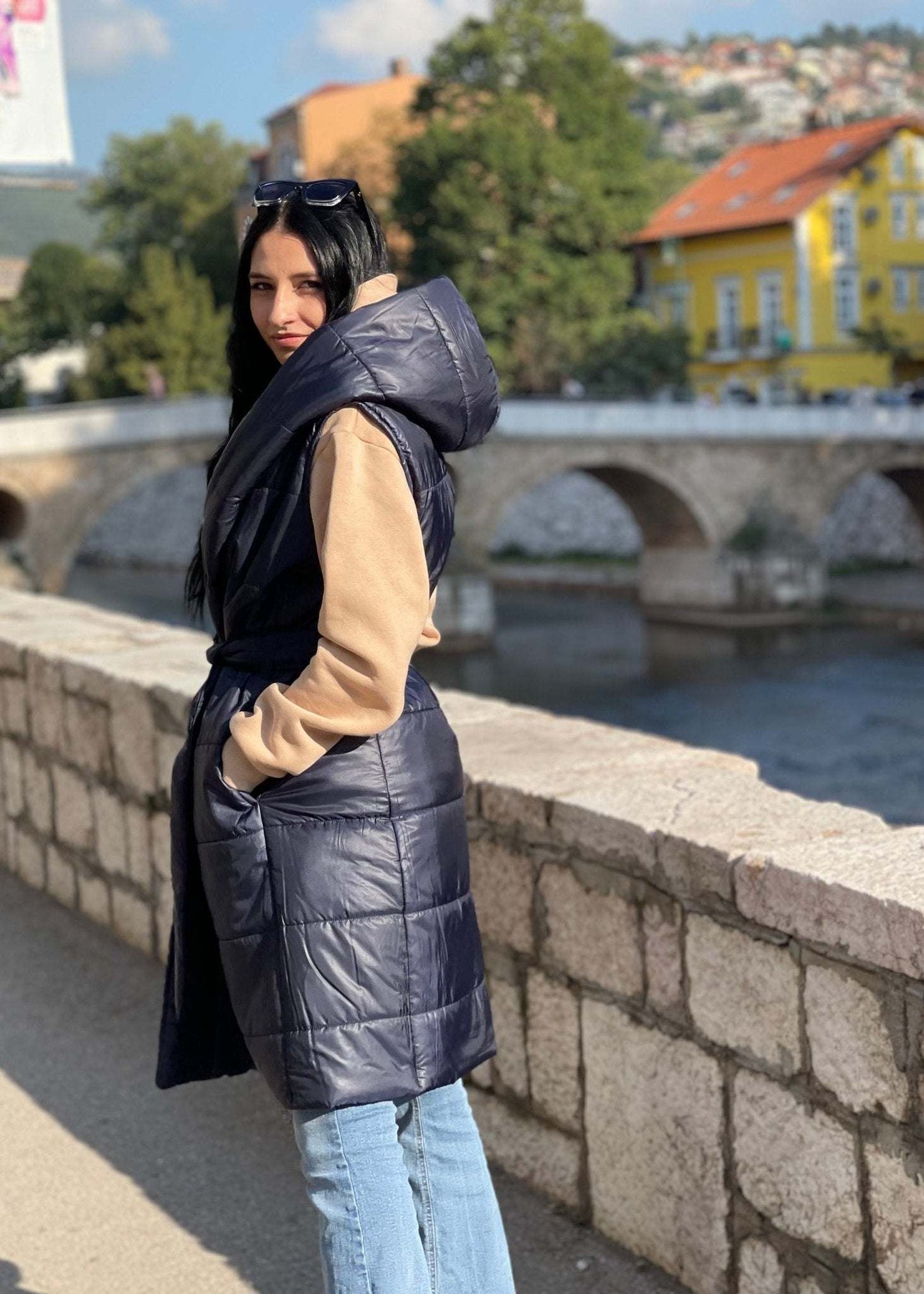 Žena nosi tamno plavi dugi prsluk s preklopom od toplog materijala za elegantan i udoban izgled na ulici