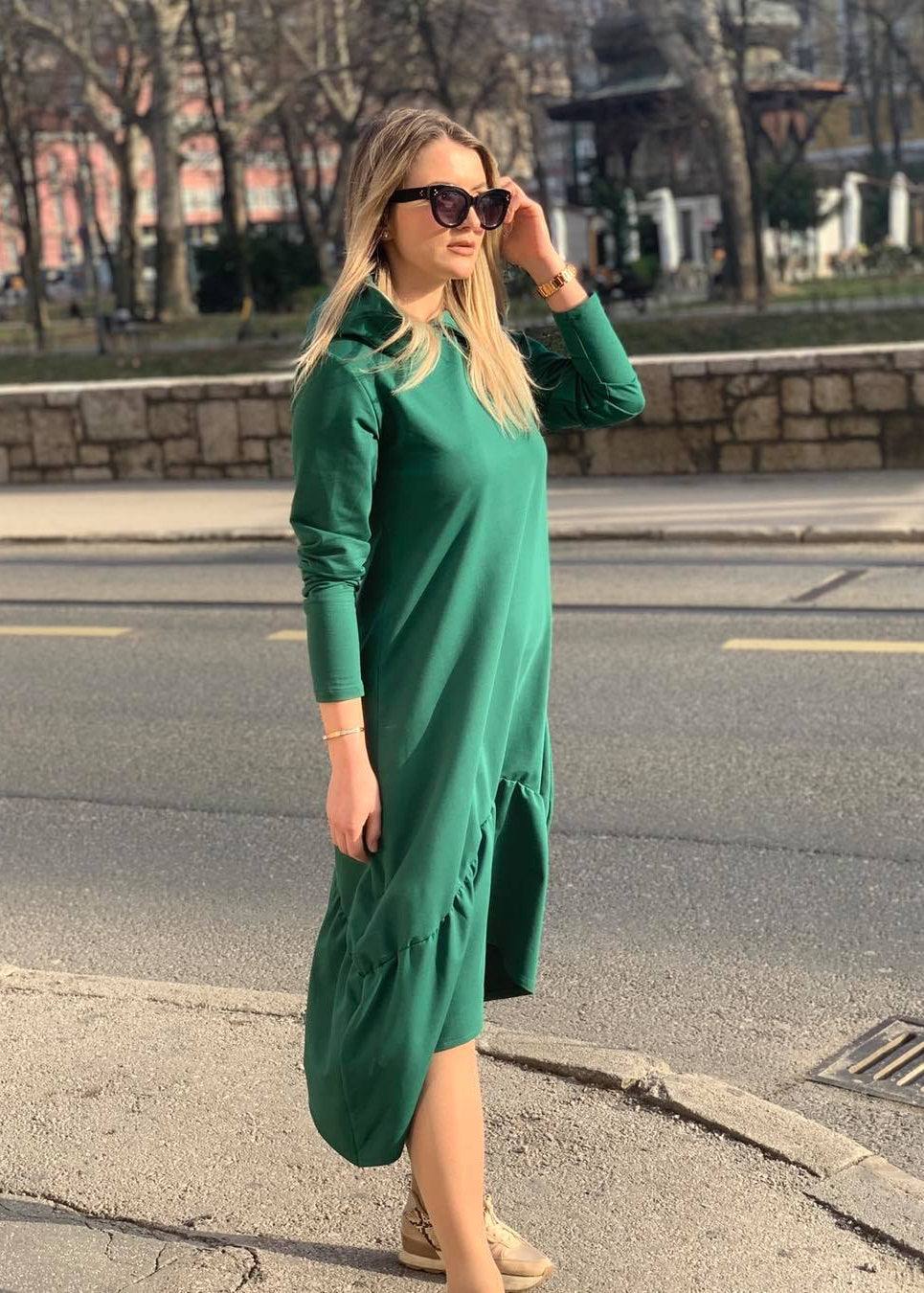 Žena u zelenoj midi haljini Demy Volan s kapuljačom, dugim rukavima i volanom na dnu.