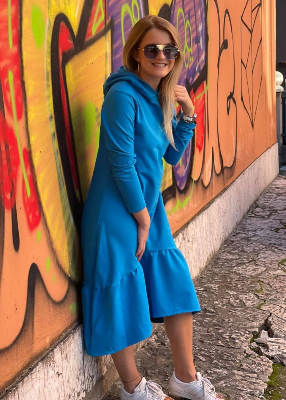 Žena u plavoj midi haljini Demy Volan s kapuljačom, dugim rukavima i volanom na dnu.