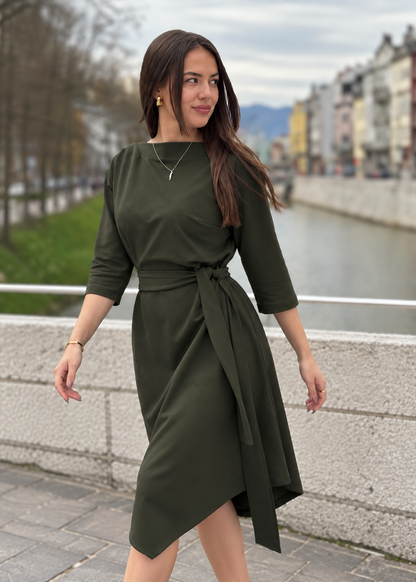 Žena u elegantnoj maslinastozelenoj midi haljini V s pojasom i 3/4 rukavima.