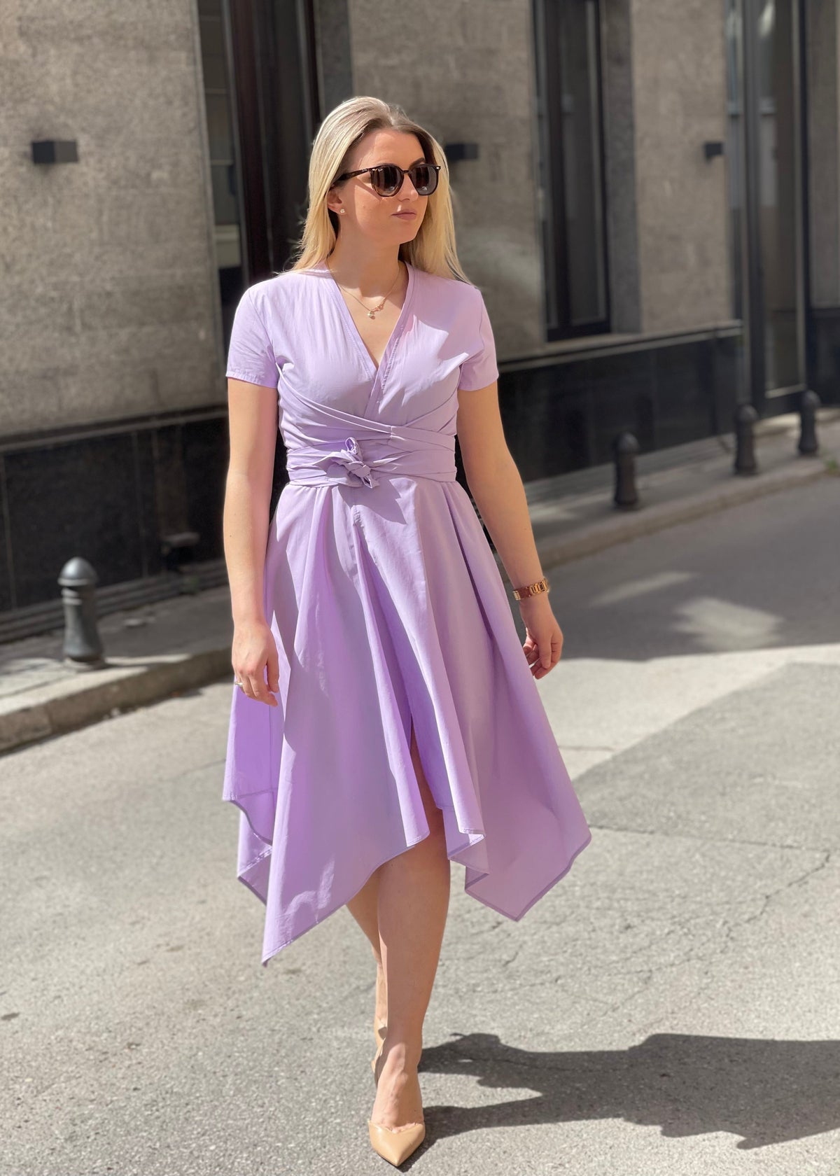 Žena u lila asimetričnoj haljini na ulici, prednja strana.