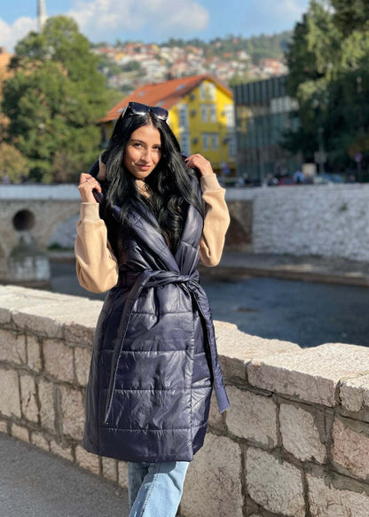 Žena nosi tamno plavi dugi prsluk s preklopom od toplog materijala za elegantan i udoban izgled na ulici