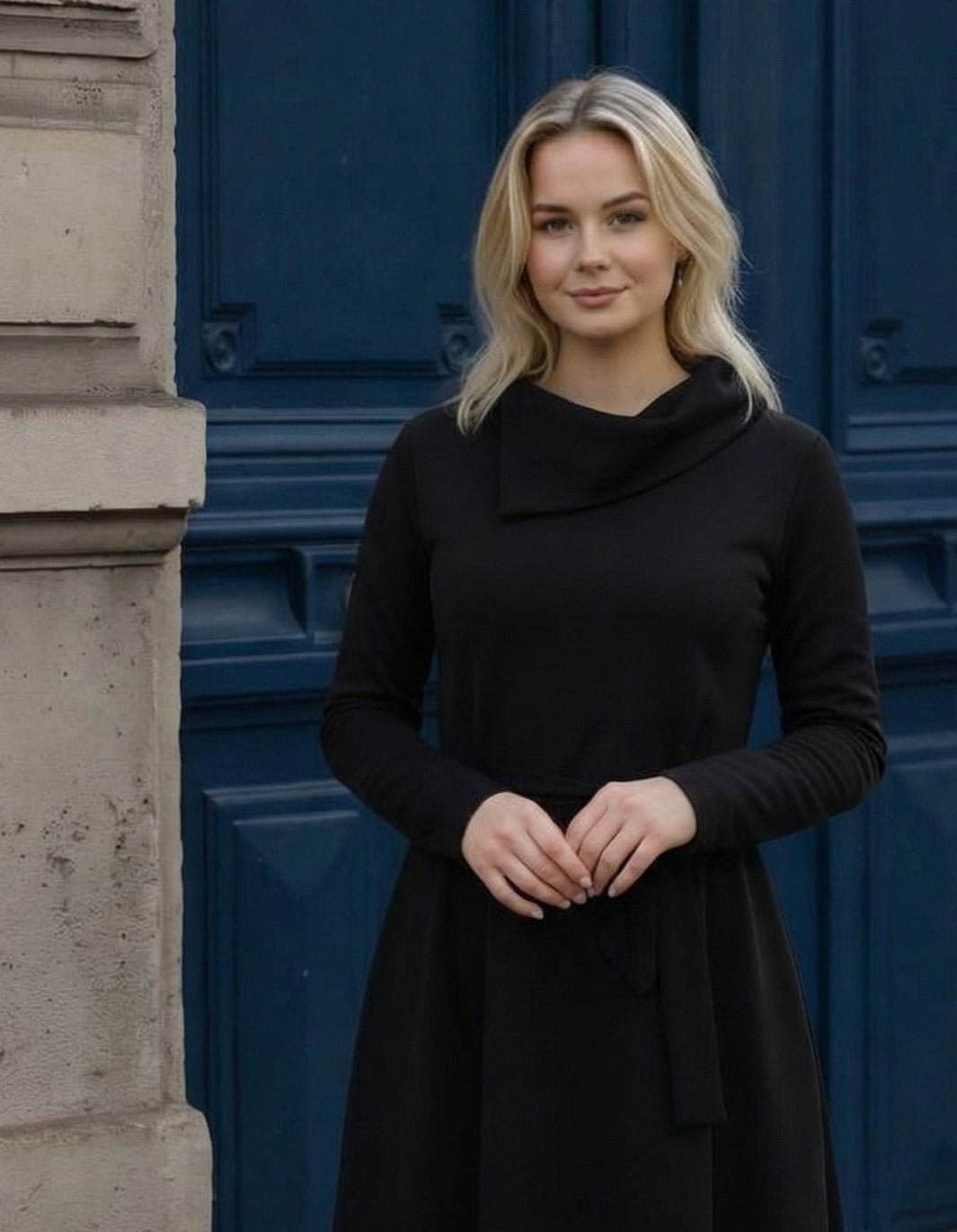 Žena nosi Anita midi crnu  haljinu A kroja s pojasom u struku.