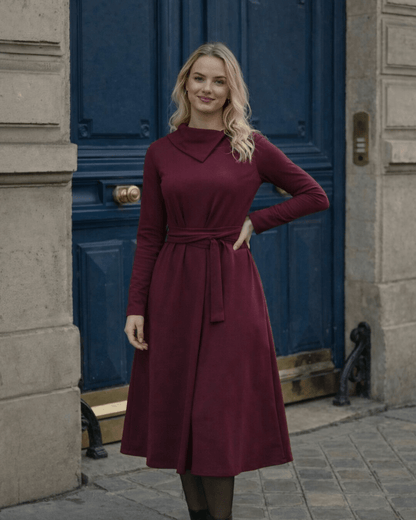 Žena nosi Anita midi bordo  haljinu A kroja s pojasom u struku.