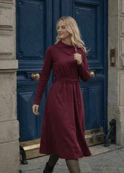 Žena nosi Anita midi bordo  haljinu A kroja s pojasom u struku.