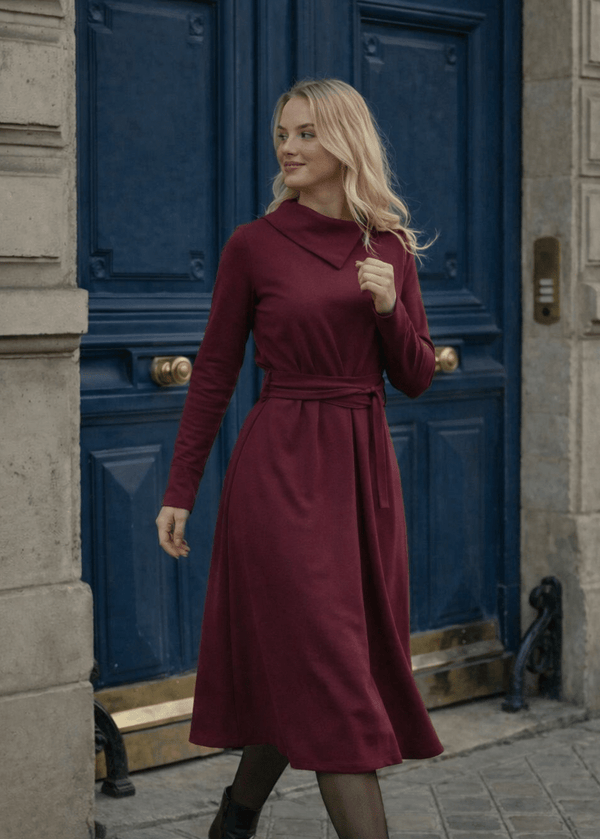 Žena nosi Anita midi bordo  haljinu A kroja s pojasom u struku.