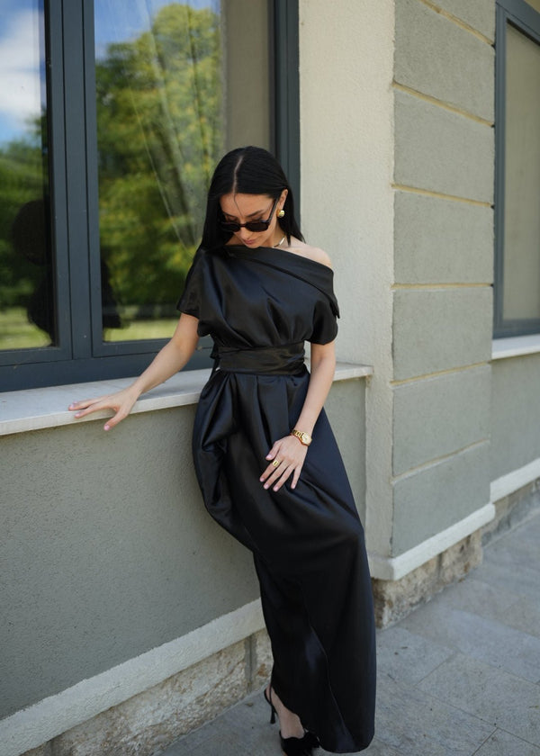 Žena u elegantnoj crnoj satenskoj haljini Atena s asimetričnim krojem, za posebne prilike