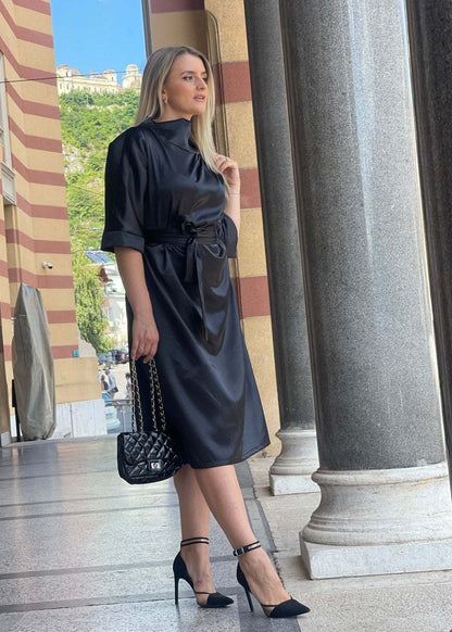 Elegantna satenska crna midi haljina Revija s okovratnikom i pojasom u struku.