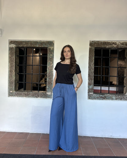 Sindy crna majica uz plave široke pantalone — bočni pogled s rukama u džepovima