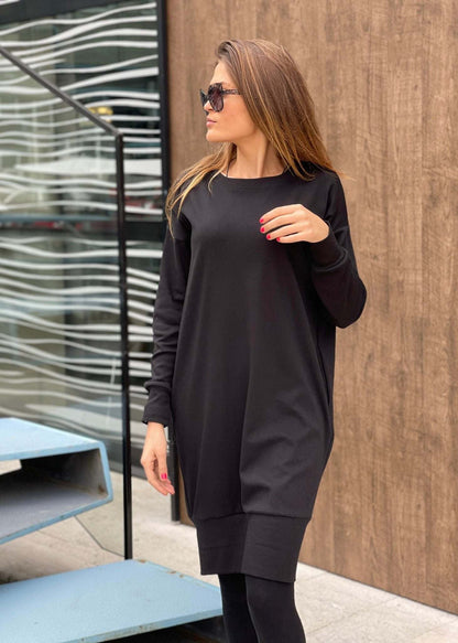 Woman wearing a black oversized midi dress "Jasna" with round neckline and long sleeves outdoors