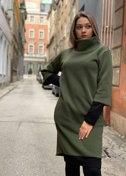 Woman wearing olive green turtle midi dress with high collar and three-quarter sleeves on city street