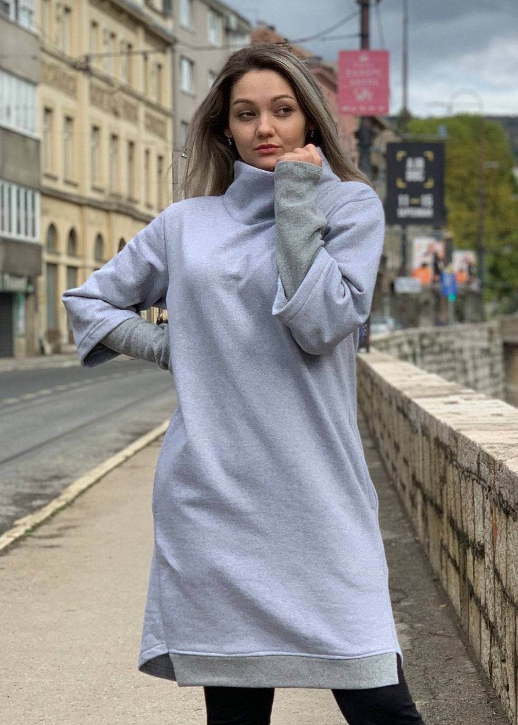 Žena u termo haljini stoji na urbanoj ulici.