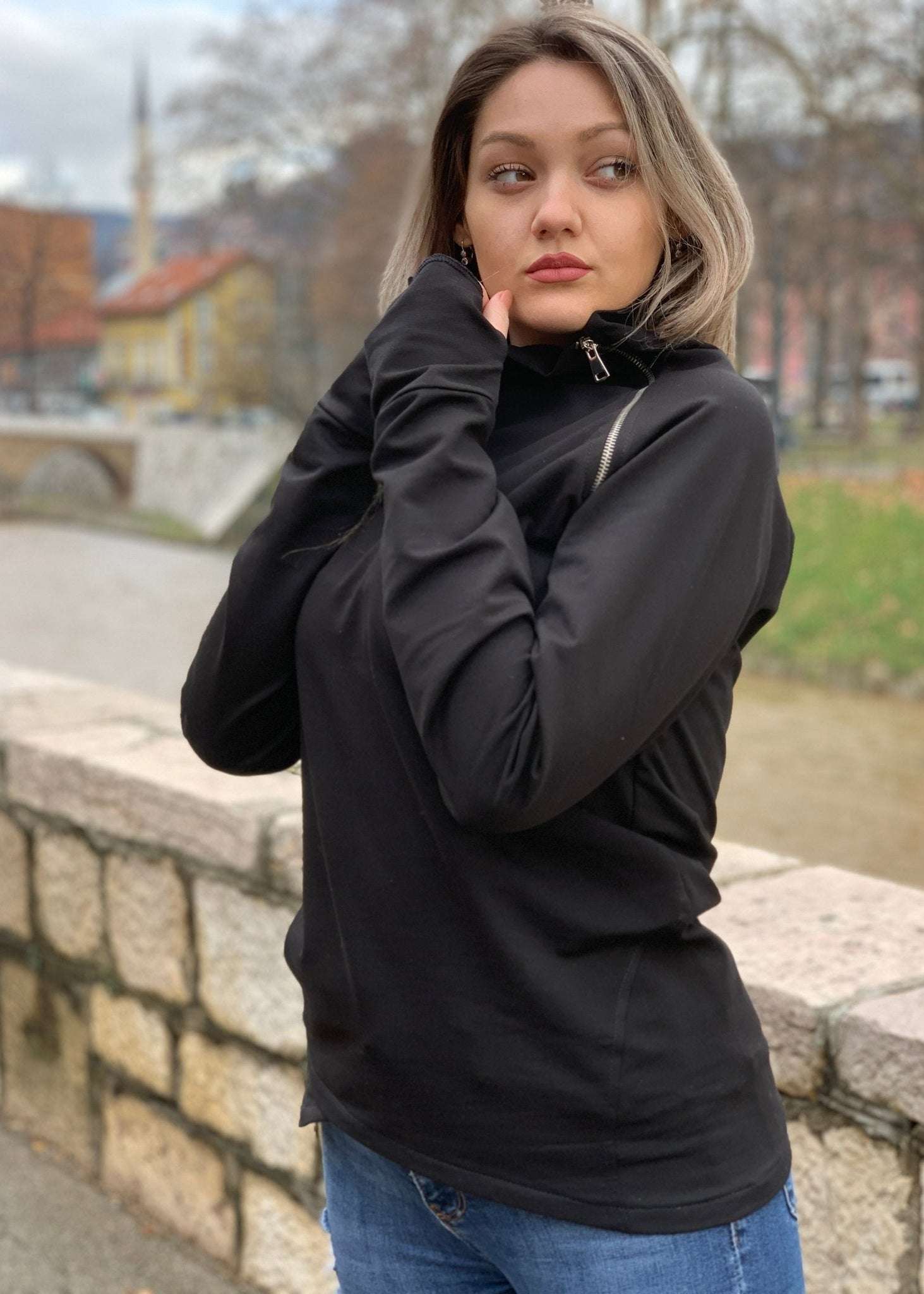 Žena u crnoj majici s asimetričnim rajfešlusom, visokim ovratnikom i dugim rukavima