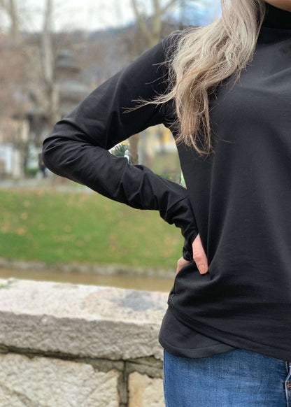 Žena u crnoj majici s asimetričnim rajfešlusom, visokim ovratnikom i dugim rukavima