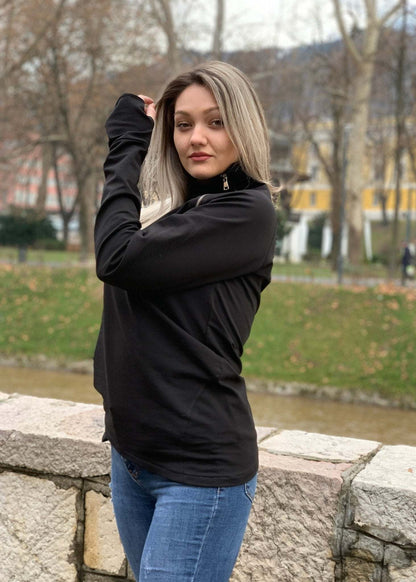 Žena u crnoj majici s asimetričnim rajfešlusom, visokim ovratnikom i dugim rukavima