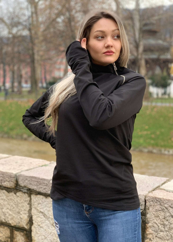 Žena u crnoj majici s asimetričnim rajfešlusom, visokim ovratnikom i dugim rukavima