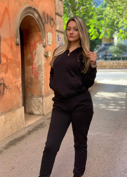 Žena u crnoj trenerci s rajsferšlusom, stoji vani pored luka.