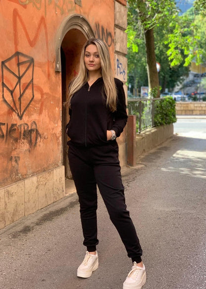 Žena u crnoj trenerci s rajsferšlusom, stoji vani pored luka.